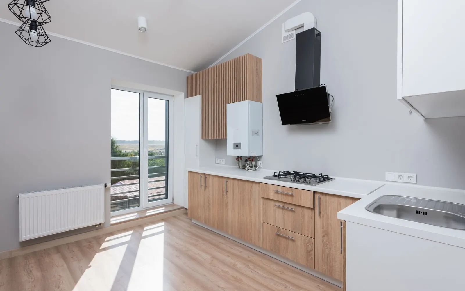A kitchen with wood cabinetry and large windows
